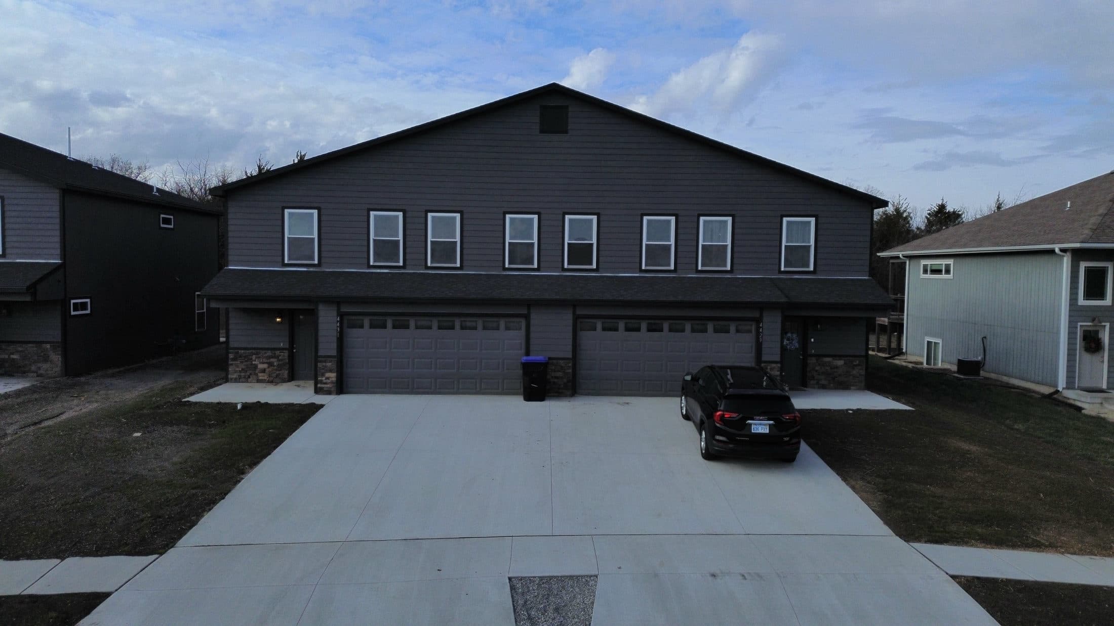 A finished Mahnopoly duplex at dusk, with warm porch lighting.
