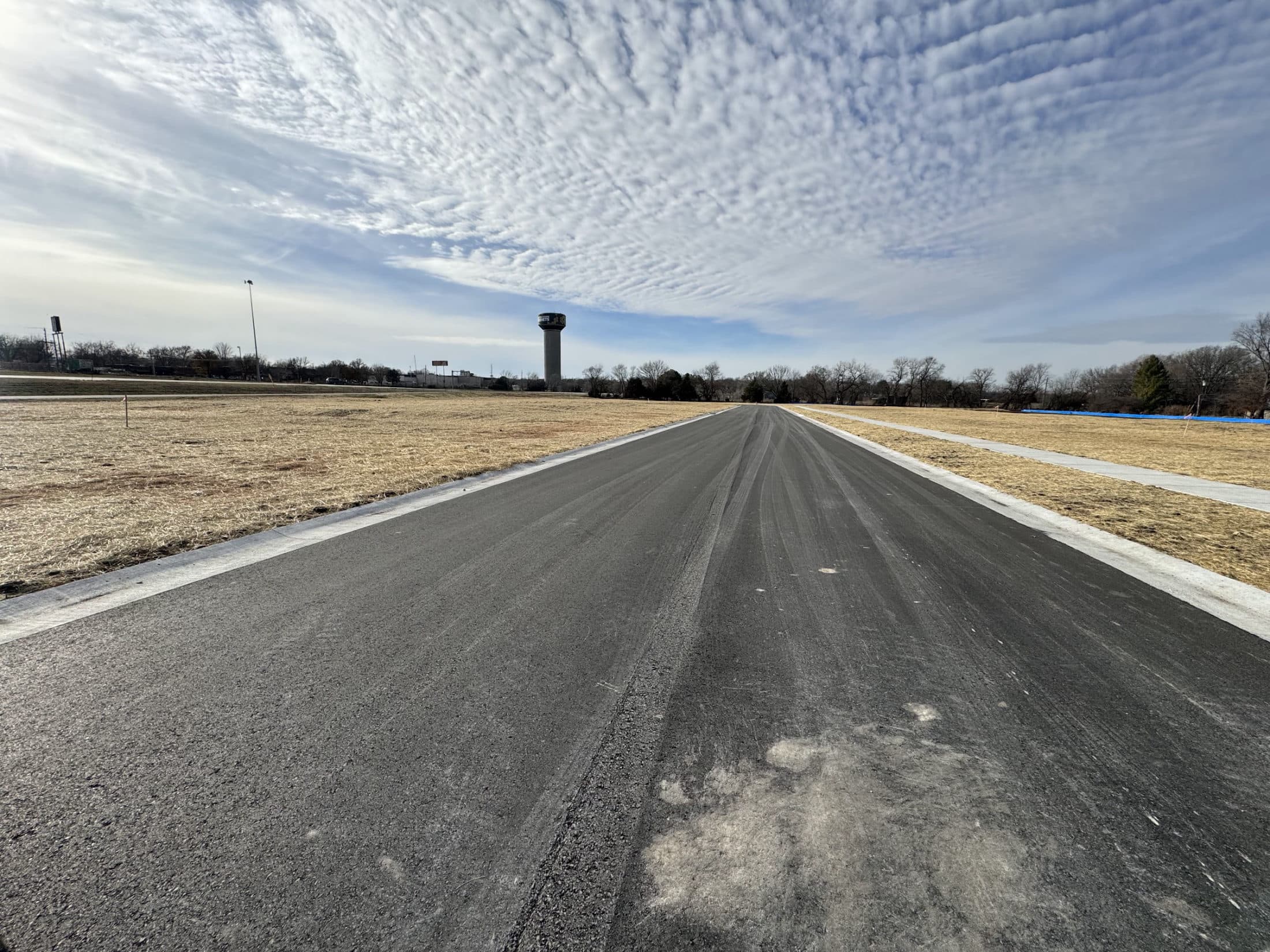 Ground-level view down the finished Mahnopoly Avenue, with a water tower in the distance.